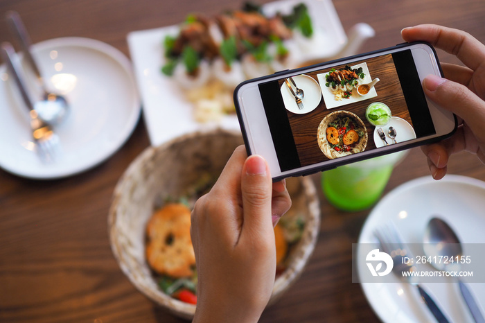 The hand of a woman take pictures of food made by herself. Food sellers take photo with a smartphone