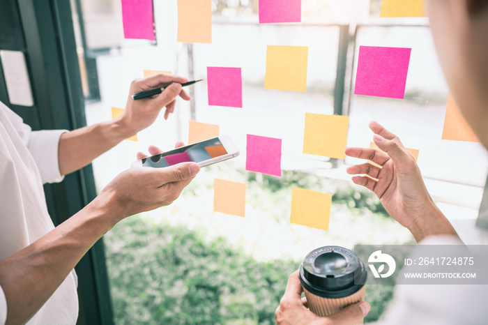 Business people meeting at office and use sticky notes on glass wall in office, diverse employees pe