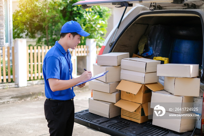 Young delivery man in blue uniform checking product boxes to send to customers on transportation veh