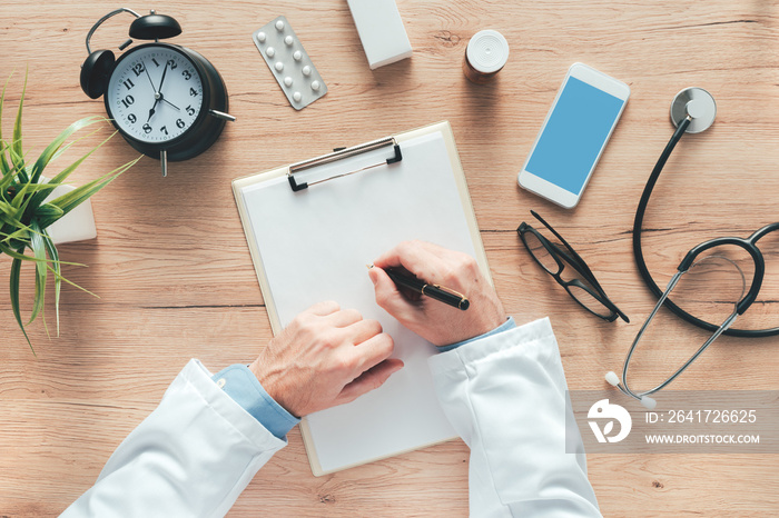 Male doctor writing notes on clipboard paper during medical exam