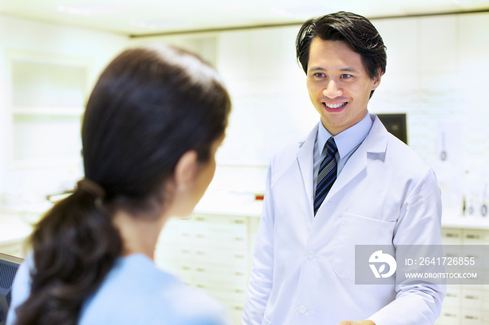 Male pharmacist handing prescription to customer