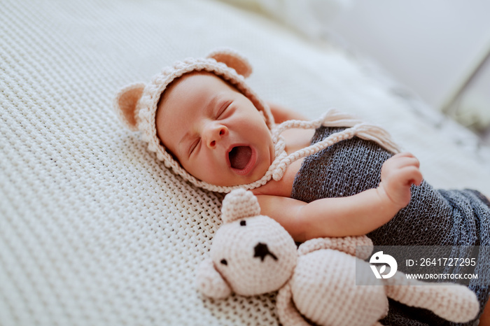 可爱的新生儿侧视图，裹着羊毛围巾，头上戴着小帽子，躺在旁边