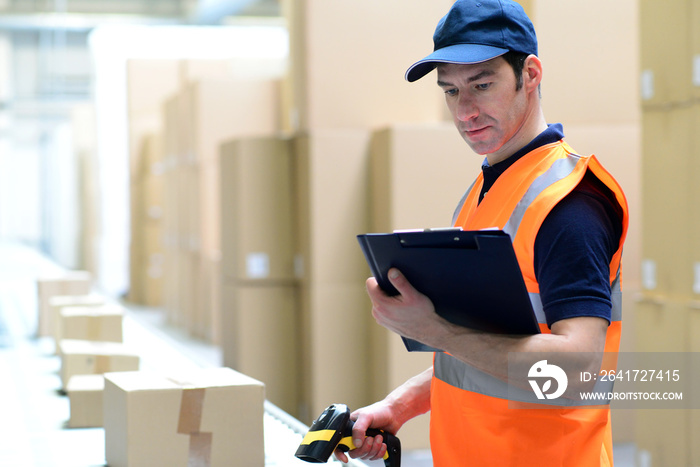 Arbeiter im Versandhandel scannt Paket für den Transport ein // Mail order worker scans package for 