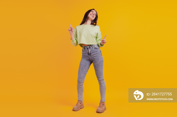 Full body photo of young cheerful girl have fun dance pointing fingers isolated on yellow color back