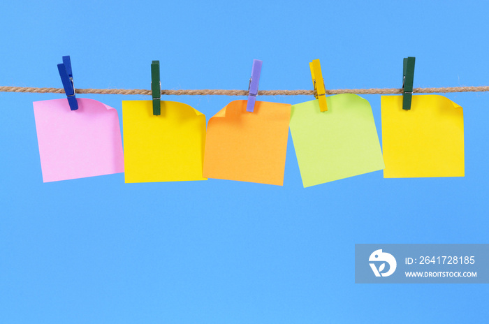 Blank sticky post it notes on a rope or clothesline plain blue backgound photo