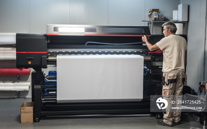 技术员操作员在大型高级工业打印机绘图仪上工作