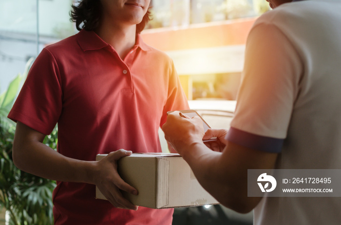 young man customer appending signature in digital mobile phone receiving parcel post box from courie