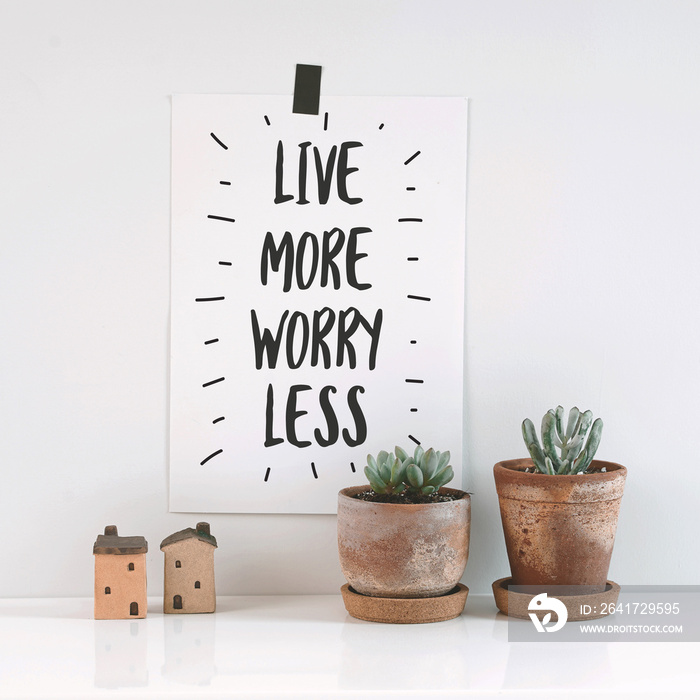 Inspirational quote  live more, worry less . Cactus in clay pots over white background.