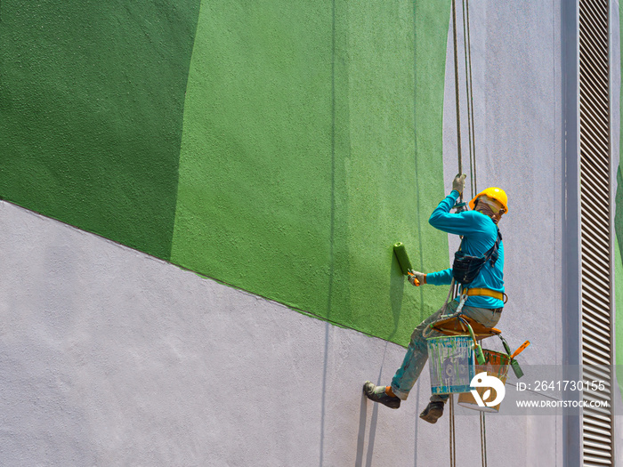 One painter is painting the exterior of the building on a dangerous looking scaffolding hanging from