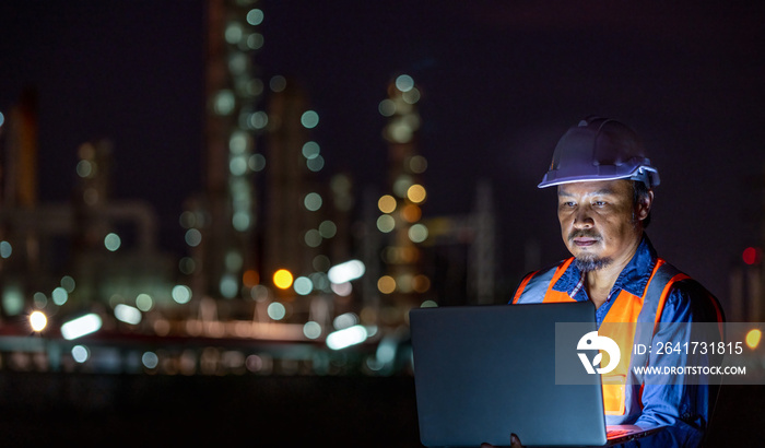 Engineer wearing safety uniform and helmet looking detail tablet on hand with oil refinery factory a