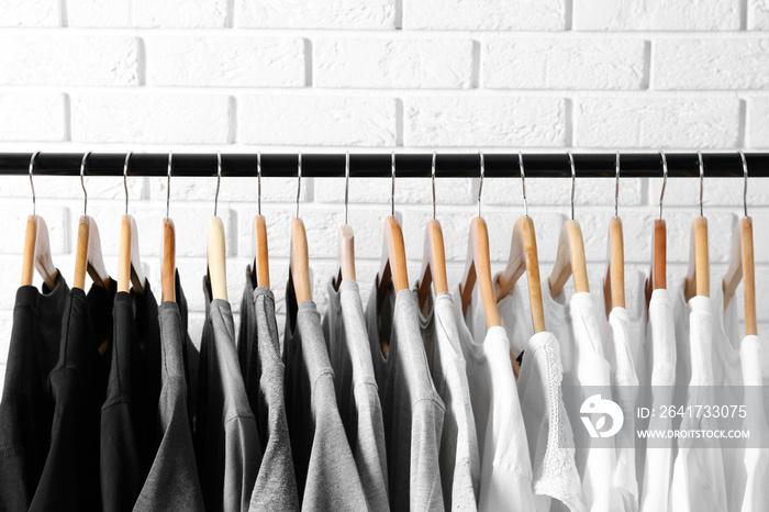 Black, grey and white t-shirts on hangers against brick wall