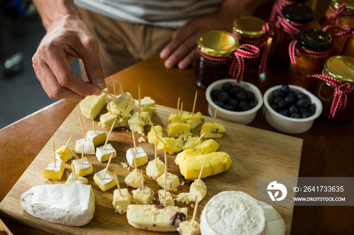 Staff arranging piece of cheese on wooden board in grocery shop