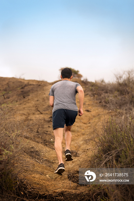 Rear view of man running on dirt road