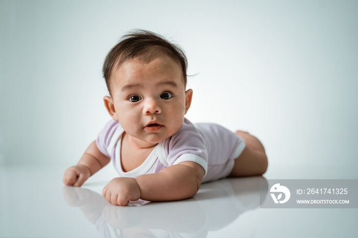 婴儿趴在她的肚子上。肚子时间可爱的婴儿在白色背景的工作室肖像