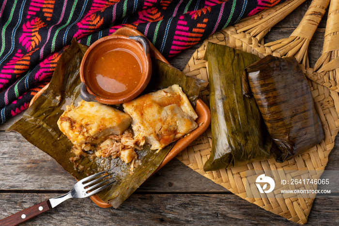 Mexican tamales wrapped in banana leaves also called  oaxaqueños  on wooden background