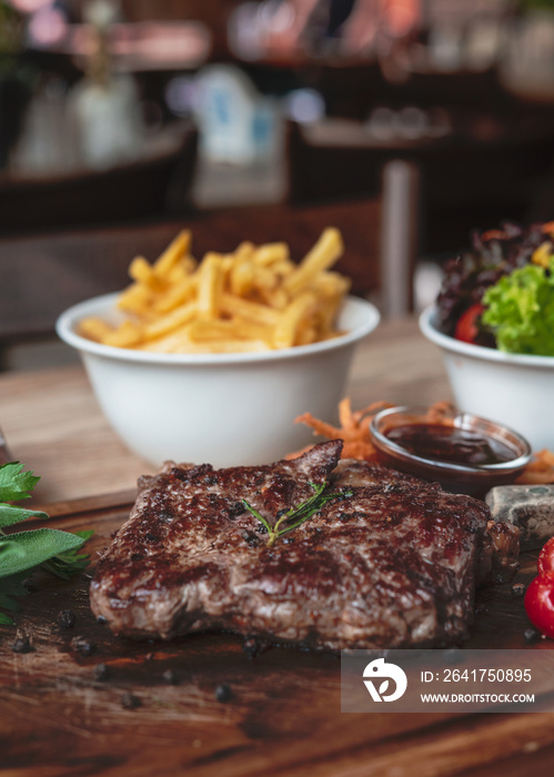 Rinder Steak mit Pommes Fries und Beilagen Salat im Wirtshaus Restaurant auf einem Holzbrett servier