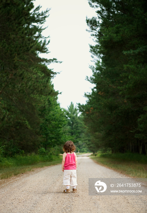 Girl standing on dirt track in forest