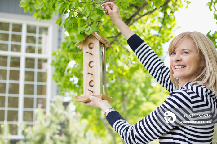 mature woman hanging a bird feeder