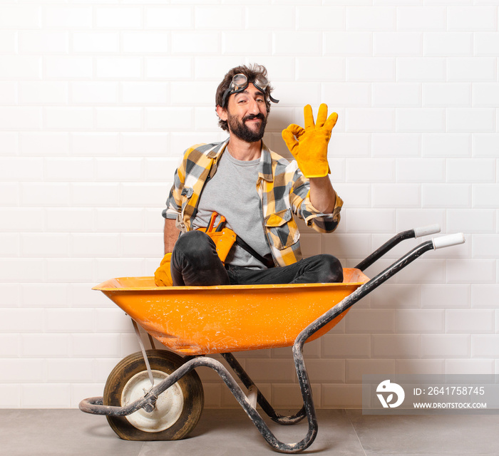 young bearded construction worker man on a wheelbarrow