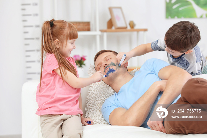 Little children painting their fathers face while he sleeping. April fools day prank