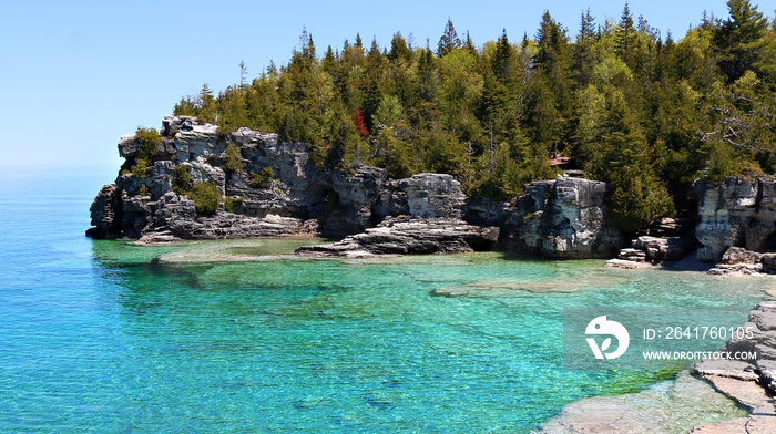 View of the turquoise clear water and rocky cliff shoreline of the Grotto park near Tobermory Ontari