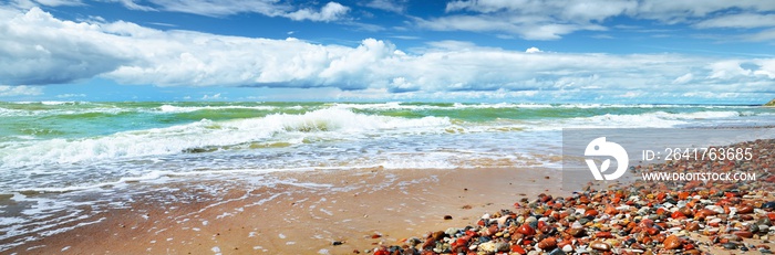 Sandy Baltic sea shore on a sunny day. Ventspils, Latvia. Dramatic blue sky with lots of cumulus clo