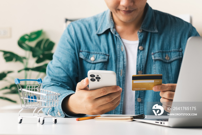 商人手持信用卡，在下单时使用智能手机进行网上购物