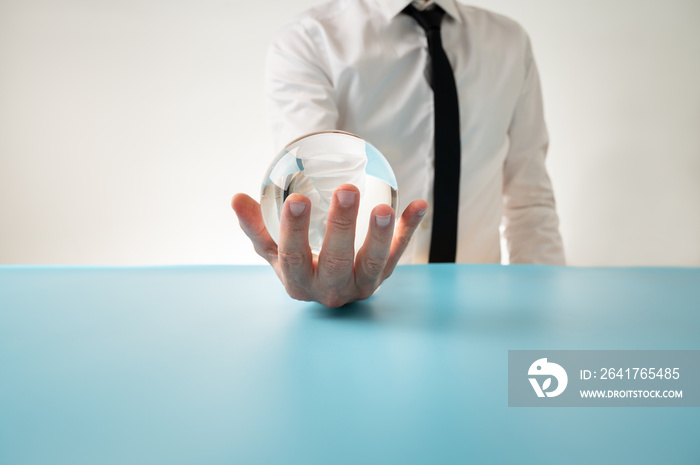 Front view of a man in elegant shirt and tie holding crystal sphere in his hand