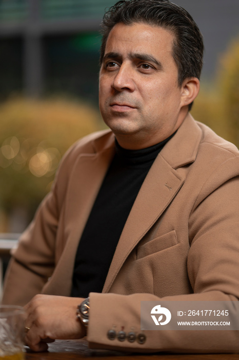 Mature man in beige coat sitting at desk