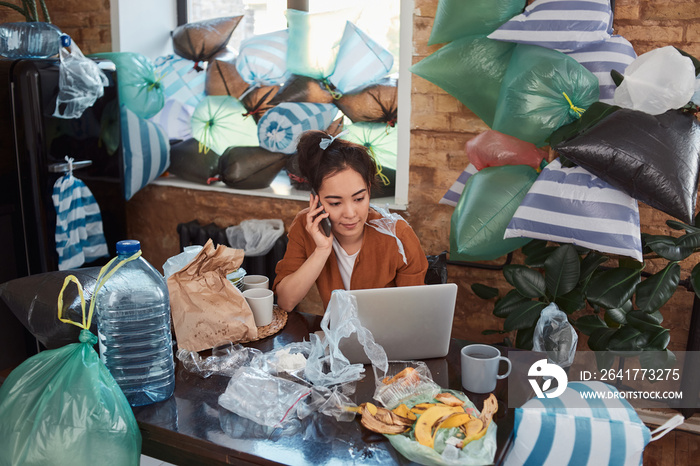 Slatternly Asian woman spending time indoors among piles of garbage