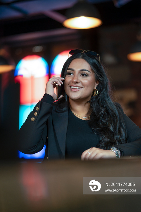 Smiling woman talking on phone in bar