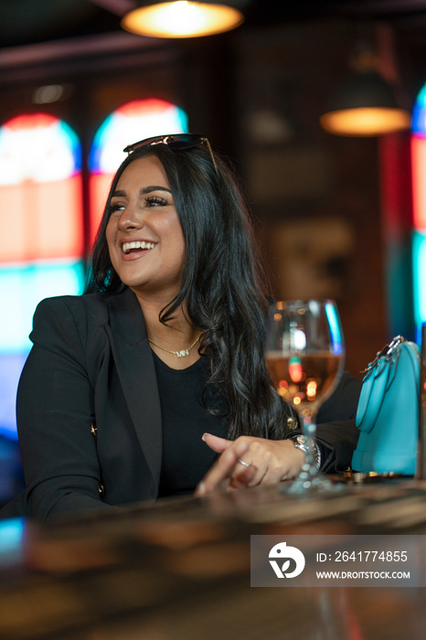 Smiling woman drinking wine in bar