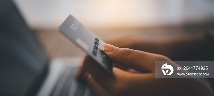 女性手拿信用卡在笔记本电脑上工作网上购物的在线支付