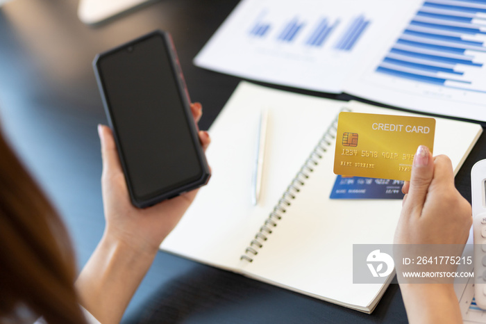 Woman holding credit card and using mobile phone shopping online. Close-up woman holding credit card