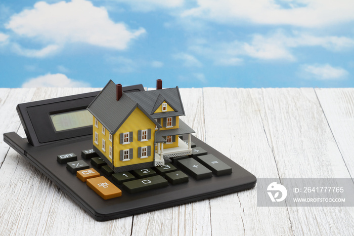 Model house on a calculator with clear blue sky