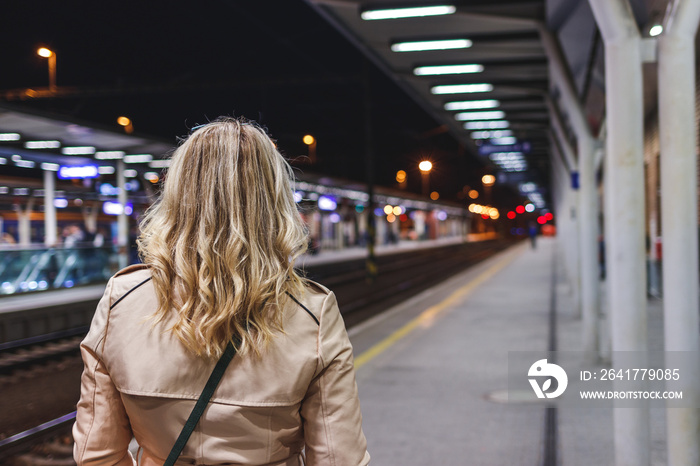 Woman waiting for train at railroad station. Public transportation. Commuter travel by train. City l