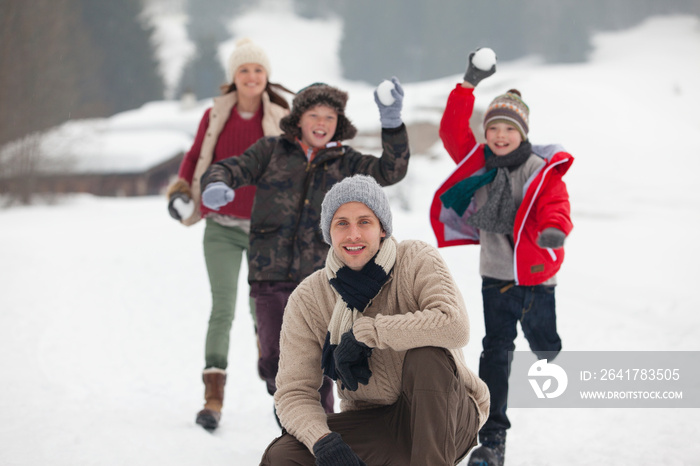 Portrait playful family enjoying snowball fight in snowy field