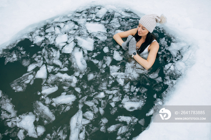 Winter swimming. Woman in frozen lake ice hole. Swimmers wellness in icy water. How to swim in cold 