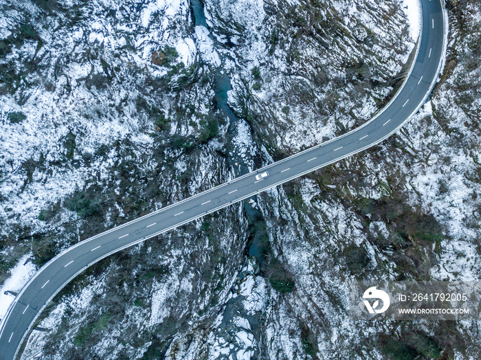 Aerial view of road bridge in Switzerland over a deep valley in winter with snow covered ground. Icy