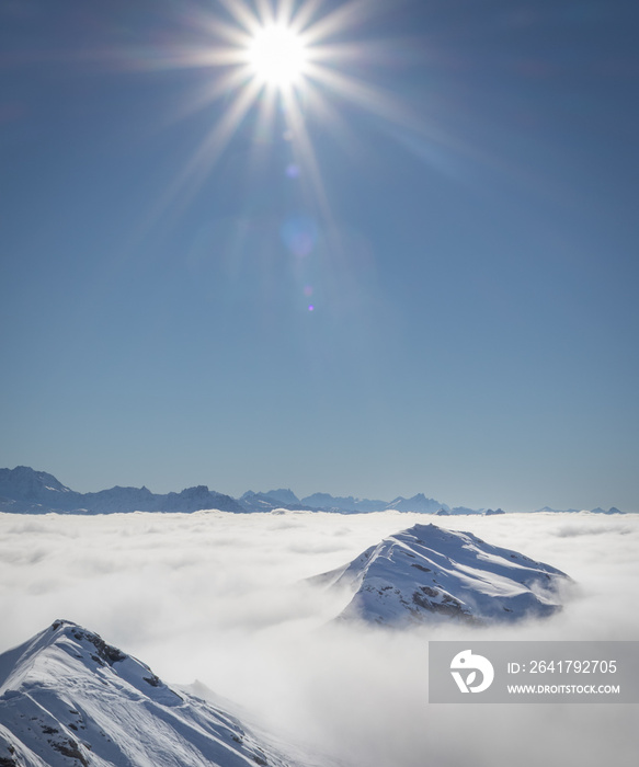 Mountain peaks covered in snow above clouds in La Plagne, French Alps