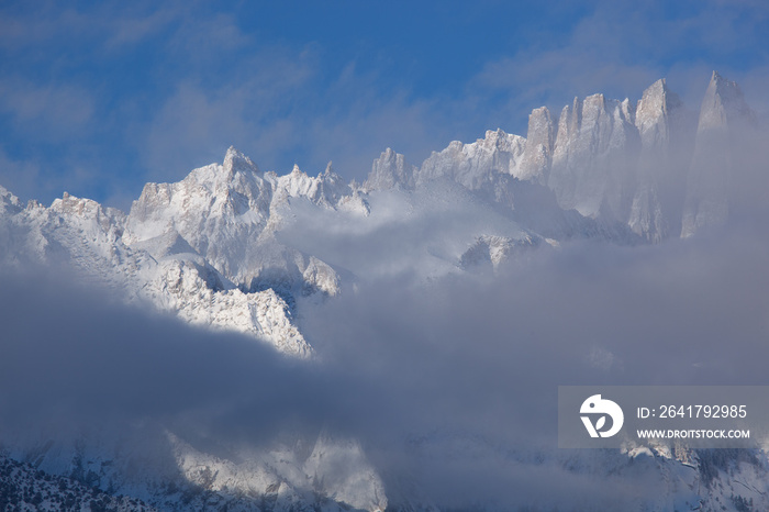 Winter landscape of the Eastern Sierra Nevada Mountains covered in snow and framed by fog and clouds