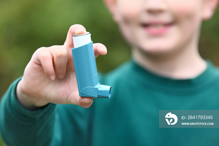 Boy with inhaler outdoors on spring day, closeup