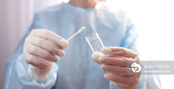 Doctor or nurse in protective gloves holds test tube and cotton swab in his hands for a test to chec