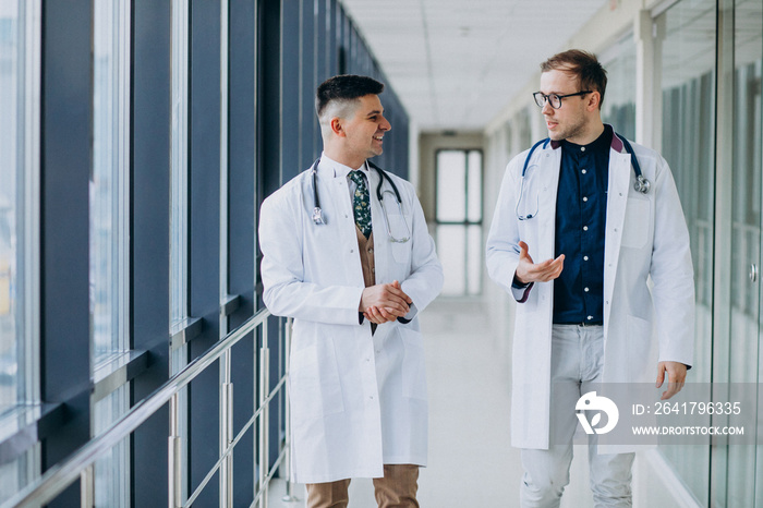 Two male doctors,walking at clinic, wearing white lab coats