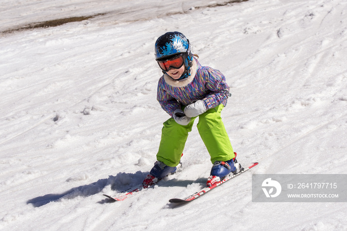 阳光明媚的山区，女孩在松软的雪地里滑雪
