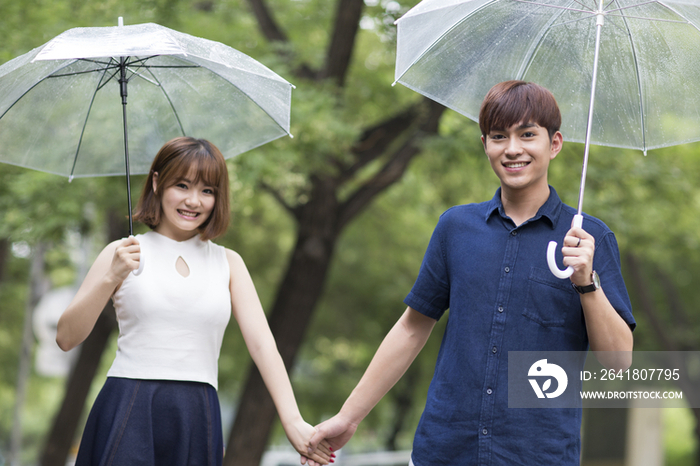 年轻情侣打着雨伞散步