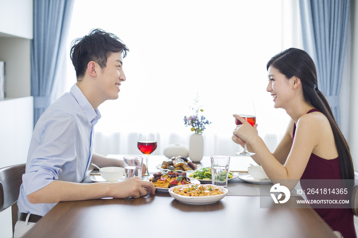 年轻夫妇在家喝红酒吃午餐