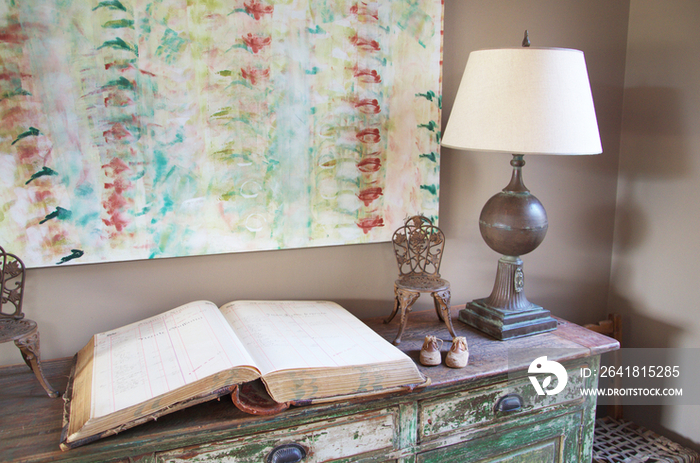 Open book and lamp on sideboard