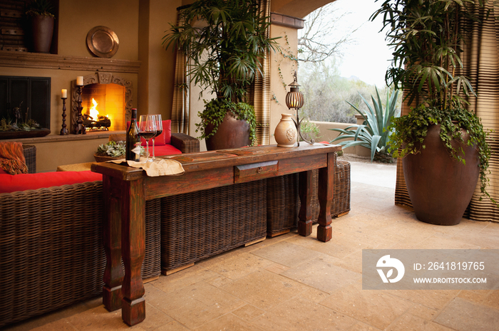 End table against wicker furniture and lit fireplace in living room at home; Scottsdale; USA