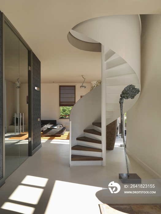 Spiral stairs along hallway with view of sitting area in the background at home